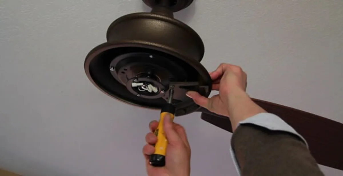Electrician installing ceiling fan mounting bracket and fixture in Waltham, MA