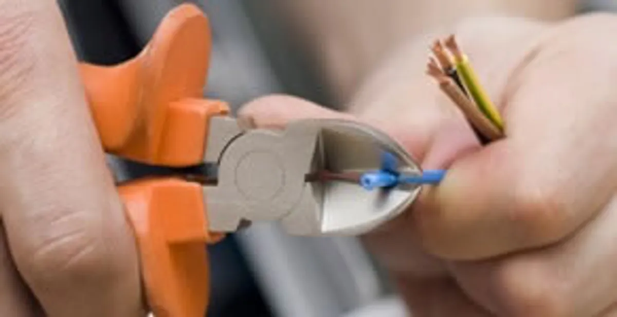 licensed electrician performing precise wire cutting and preparation during electrical service in Waltham, MA